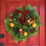 Cinnamon Spice Christmas Wreath A festive cinnamon spice wreath hanging on a red door, decorated with pinecones, dried oranges, lotus pods, cinnamon sticks, glossy copper baubles, and a large red velvet bow. 1
