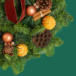 Cinnamon Spice Christmas Wreath Close-up section of a cinnamon spice wreath showing detailed textures of pinecones, dried oranges, copper baubles, lotus pods, cinnamon sticks, and fresh evergreen foliage. 2
