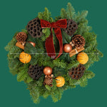 Cinnamon Spice Christmas Wreath A cinnamon spice wreath displayed against a green background, featuring a red velvet bow, pinecones, dried oranges, cinnamon sticks, lotus pods, and copper baubles, with a measurement line showing a 10-inch width. 3