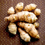 Jerusalem Artichoke Bare Roots A pile of freshly harvested Jerusalem artichoke tubers with knobbly, tan-coloured skins arranged on a woven surface. 1