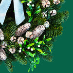 Mistletoe Kisses Christmas Wreath Close-up of the Mistletoe Kisses wreath showing frosted pinecones, glossy green mistletoe leaves, white berries, and textured evergreen foliage with a hint of sparkle. 2