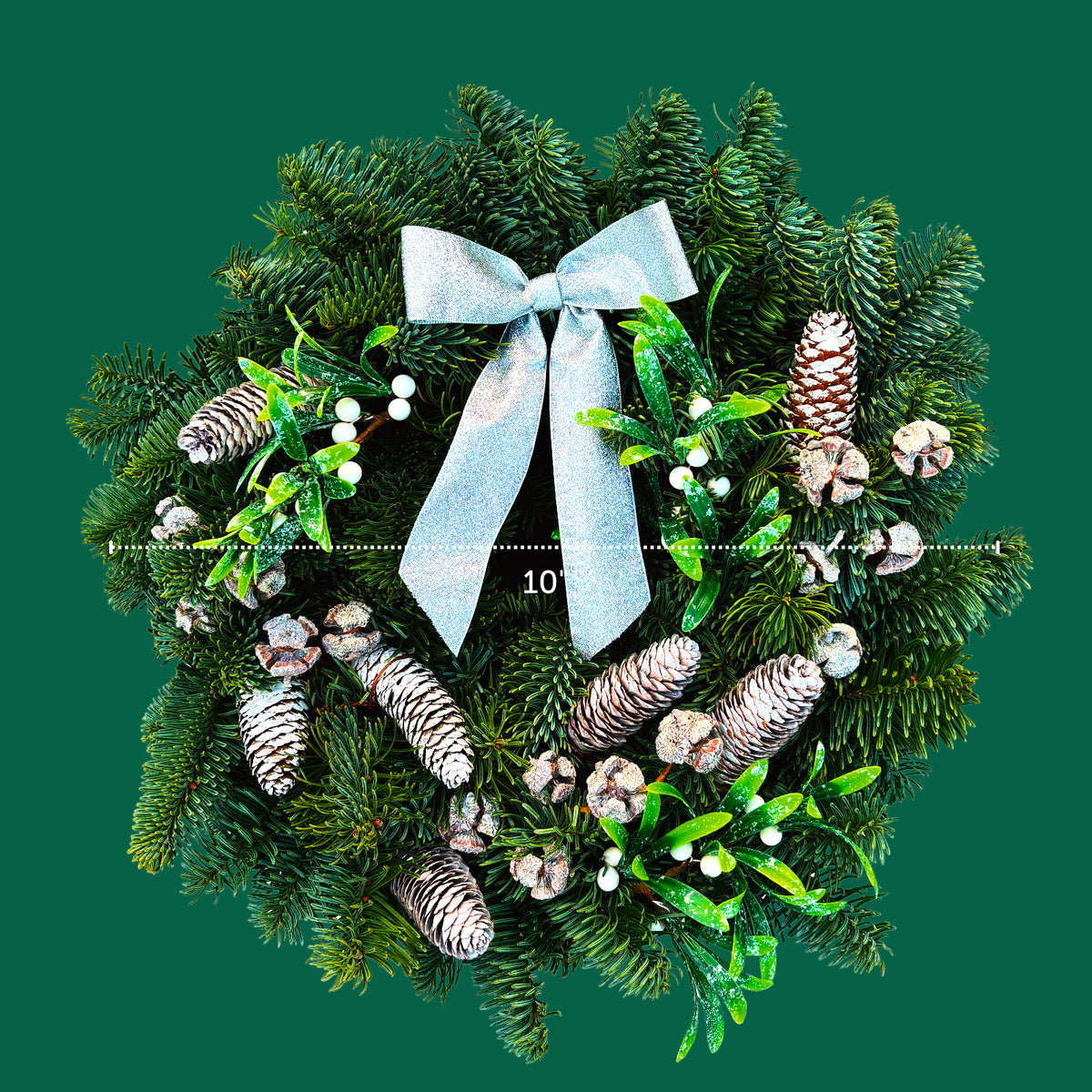Mistletoe Kisses Christmas Wreath Front view of the Mistletoe Kisses Christmas wreath on a green background, showing a 10-inch diameter with decorative pinecones, white berries, and silver bow detail. 3