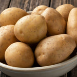 Seed Potatoes Nicola Clean Nicola seed potatoes displayed in a ceramic bowl on a rustic wooden surface, highlighting their smooth golden skins. 4