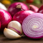 Mixed Varieties Onion Planting Sets Red onions with one cut open to reveal concentric rings, alongside cloves of pink-tinged garlic on a wooden surface. 5