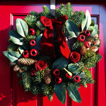 Red Rose and Rosehip Christmas Wreath A 10-inch festive wreath made from mixed evergreen foliage, pinecones, faux red berries, and velvet red roses, finished with a red ribbon bow and hung on a bright red front door. 1