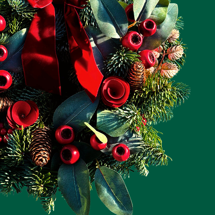 Red Rose and Rosehip Christmas Wreath Close-up of the Christmas wreath showing red rose decorations, pinecones, red berries, eucalyptus-style leaves, and textured evergreen foliage. 2