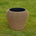 Mica Plant Pots - Light Brown Cane Large decorative wicker plant pot with curved design and grey accents, set outdoors on green grass. 4