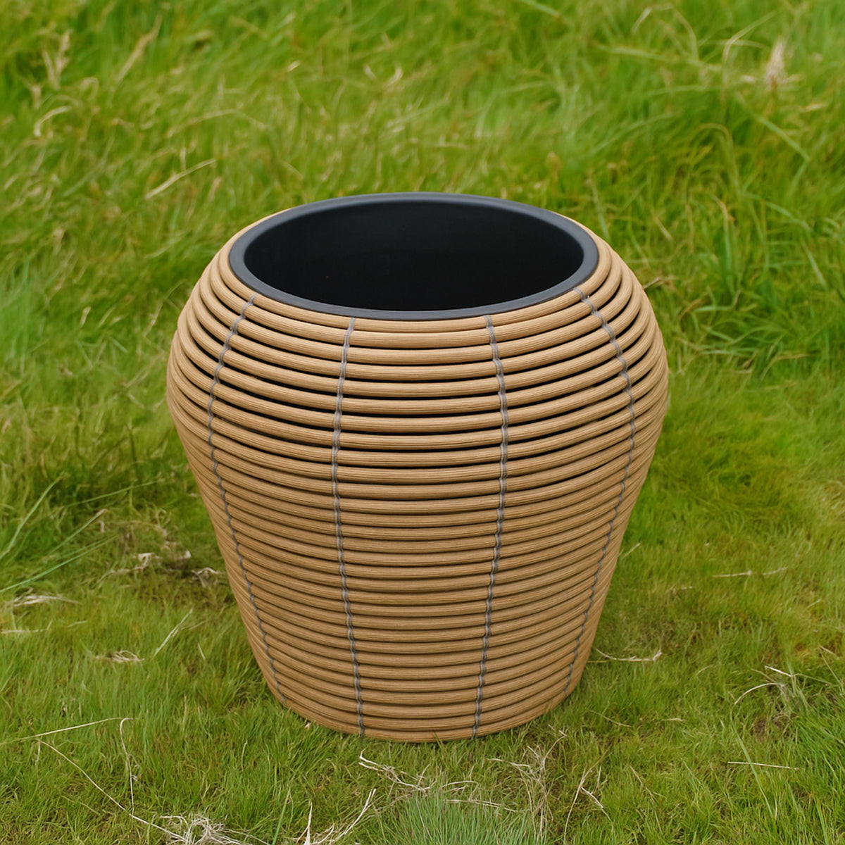Mica Plant Pots - Light Brown Cane Medium-sized wicker plant pot with a natural tan and grey weave, featured on a grass 1