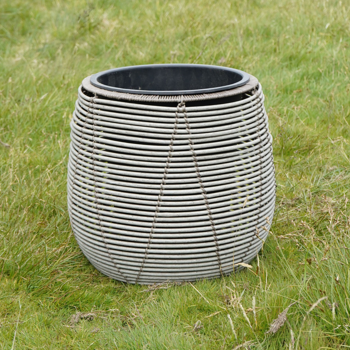 Mica Plant Pots - White Cane Large white woven-effect outdoor plant pot with rounded shape, displayed on grass. 5